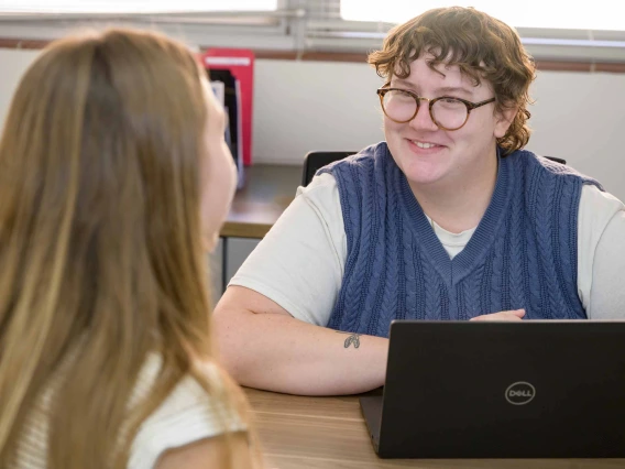 Academic advisor Adora Harvey has a lap top propped open and smiles at a student in front of her.  