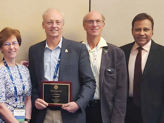 Photo of Rick G. Snellmann, holding a plaque, standing next to three people