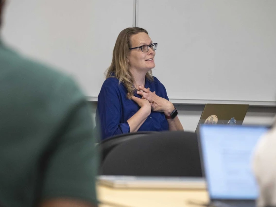 Kacey Ernst, PhD, holds her hands at her chest while talking to students.
