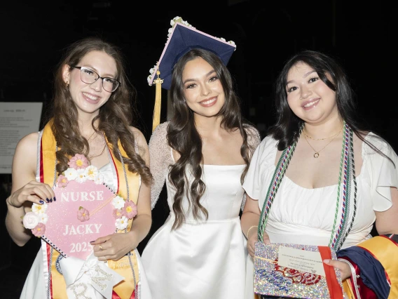 Three young women show off their graduation mortar boards as they wait backstage for the ceremony to begin. 