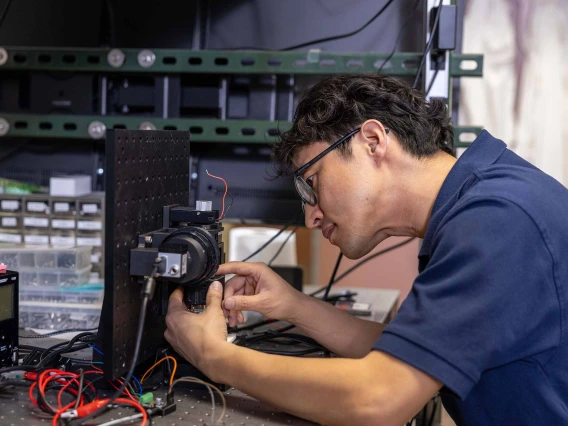 A researcher is hunched over an imaging device that he is working on in a laboratory.