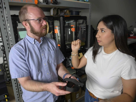 Student explains adaptive foot pedal prototype to professor in Health Sciences Design makerspace