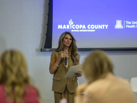 A woman stands at the front of a conference room at the Phoenix Bioscience Core, speaking into a microphone to rows of seated educators.