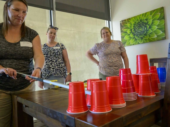 A teacher handles red cups in a hands-on therapy exercise while two other teachers watch in a classroom at the Phoenix Biomedical Campus