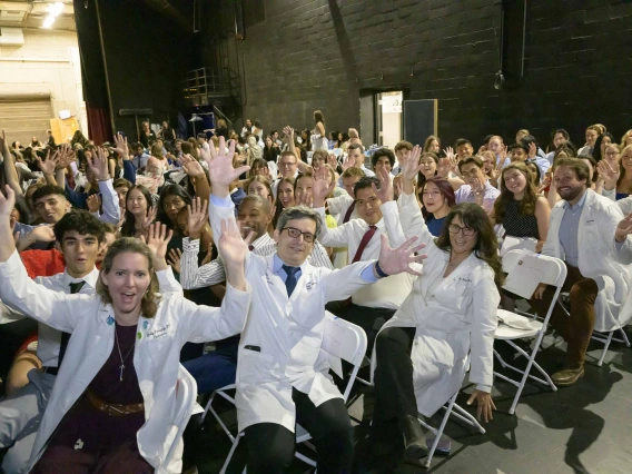 More than 100 U of A College of Medicine – Tucson professors and first-year medical students wave as they wait in chairs backstage at Centennial Hall. 