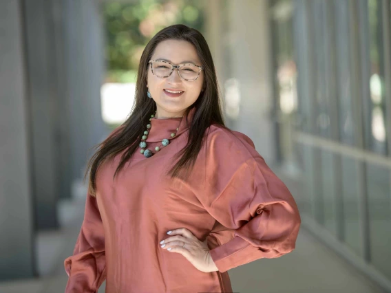 Portrait of Amanda Wilson standing in an outside corridor smiling. 