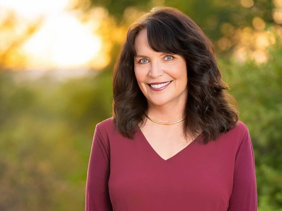 Portrait of Dr. Ann Marie Chiasson in an outdoor setting with trees behind her. 