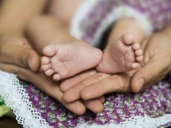 Close-up of adult hands holding baby’s feet