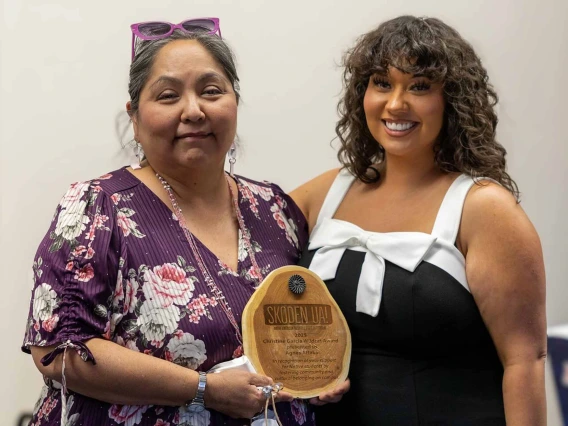 Agnes Attakai, left, holds a wooden plaque and stands next to her daughter Nadira Mitchell.