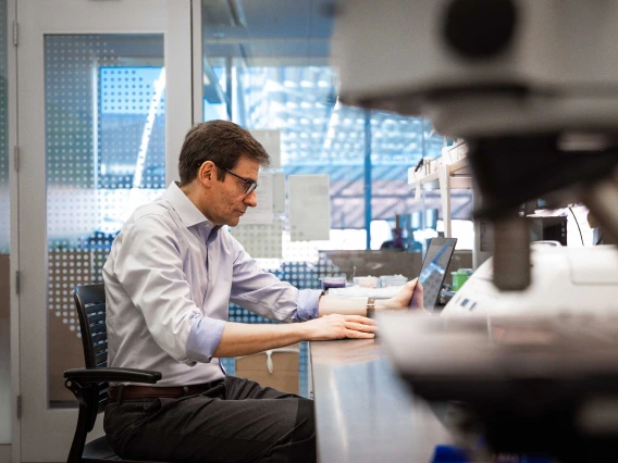 Stefano Guerra, MD, PhD, works with laptop in a lab