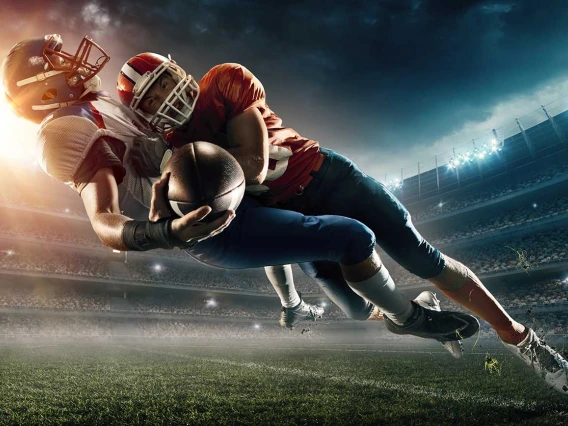 A decorative image shows two football players falling to the turf after one is tackled by the other.