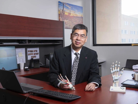 Portrait of Zong-Ming Li, PhD, in a suit and tie, seated at a desk.