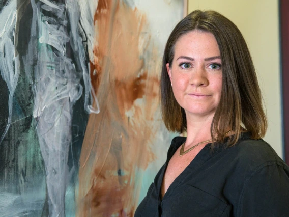 Harriet Barratt, MD, poses in front of her painting Stance, an acrylic spray paint on wood, on the fifth floor of the Health Sciences Education Building in Phoenix.