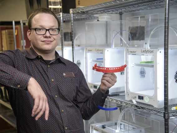 Tory Middlebrooks, of University Libraries, holds a face shield, which is designed to be worn with additional PPE such as a mask. Middlebrooks runs the 3D printers that produced the headbands for the face shields created by University of Arizona employees and students in makerspaces across campus. The effort was well underway by early April.
