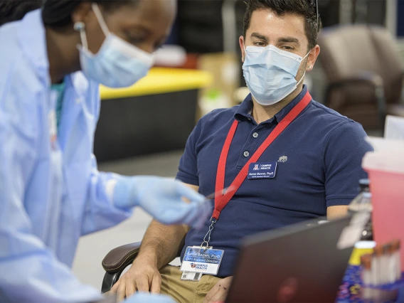 Among the essential workers receiving antibody tests, Aaron Barnes, PsyD CAPS Assistant Director of Campus Health. Barnes provides his name to health care worker before testing.