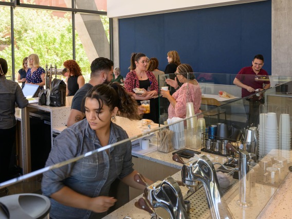 Crowd of people in a cafe with a coffee bar in the foreground. 
