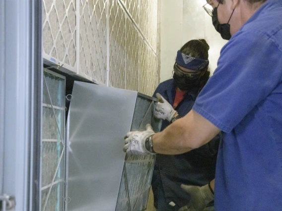 The University of Arizona Facilities Management team and key university stakeholders have worked diligently since spring 2020 to mitigate COVID-19 exposure for all students, staff and faculty. Pictured here, Facilities Management HVAC mechanics Sandra Acuna and Edward Leon install a new MERV 13 filter in the Health Sciences Innovation Building (HSIB).