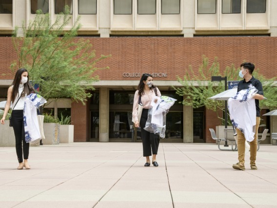 White coats in hand, three new members of the Class of 2024 leave the College of Medicine – Tucson building. From left: Lupita Molina, Julia Alvarenga Couto and Lawrence Sun.