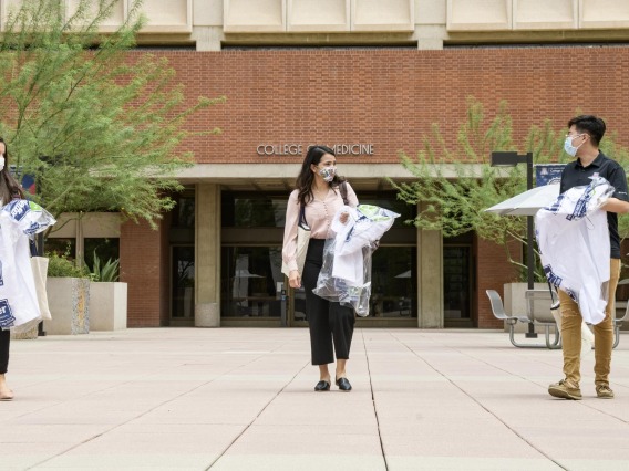 Students in the College of Medicine – Tucson Class of 2024 wear masks and keep a safe distance from one another as they pick up their white coats, the traditional activity marking the beginning of their four-year medical school experience.