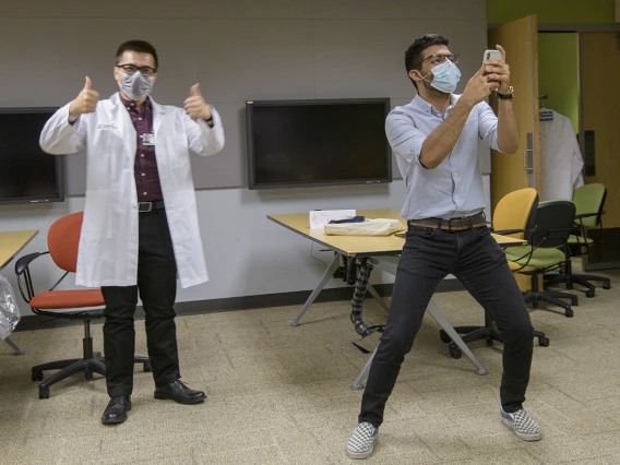 First-year medical student Daniel Nguyen of Santa Rita House tries on his white coat while first-year medical student Ahmed Al-Shamari takes a selfie with his new colleague.