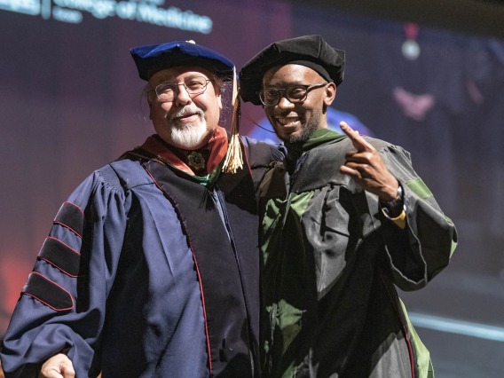 Assistant Dean of Curricular Affairs Carlos Gonzales, MD, congratulates Andrew Muse, MD, after hooding him during the College of Medicine – Tucson class of 2022 convocation at Centennial Hall.