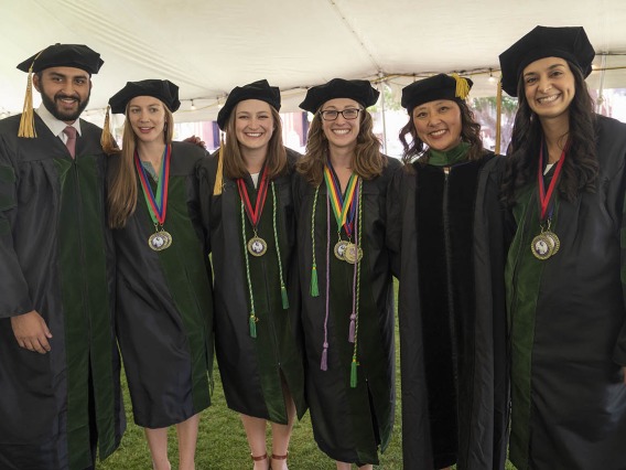 (From left) Abdullah Aleem, MD; Phoebe Bredin, MD; Abigail Slack, MD; Layne Jordan, MD; Allie Min, MD, assistant dean, career development; and Sara Ali Fermawi, MD, pose for a photo before the start of the College of Medicine – Tucson class of 2022 convocation at Centennial Hall.
