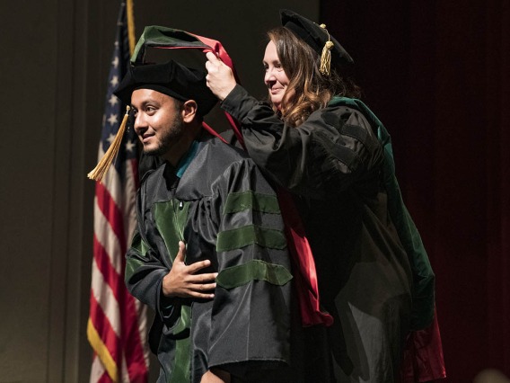 Professor Collene Cagno, MD, hoods Shirzad Shir, MD, during the College of Medicine – Tucson class of 2022 convocation at Centennial Hall.