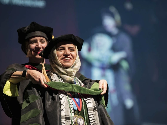 Associate Professor Mari Ricker, MD, hoods Tesneem Akram Tamimi during College of Medicine – Tucson class of 2022 convocation at Centennial Hall.