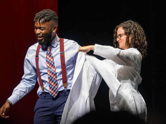 Atehkeng Zinkeng is presented his white coat by associate professor Audrey Baker, MD, during the UArizona College of Medicine – Tucson Class of 2026 white coat ceremony.