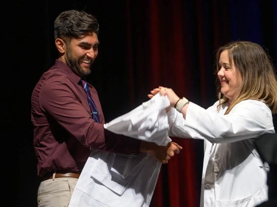 Rorie Robinson prepares to be coated by clinical assistant professor Joy Bulger Beck, MD, at the UArizona College of Medicine – Tucson Class of 2026 white coat ceremony.