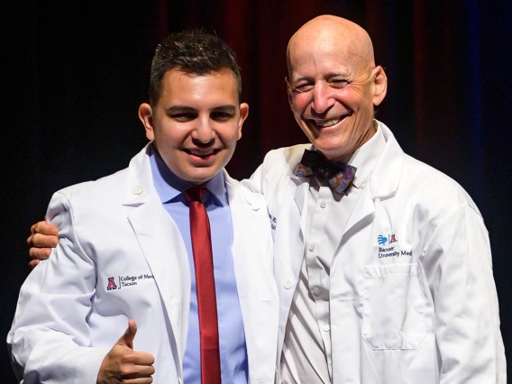 Adrian Franco pauses for a photo with professor Paul Gordon, MD, MPH, after receiving his white coat at the UArizona College of Medicine – Tucson Class of 2026 white coat ceremony.