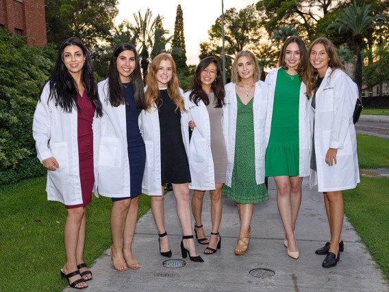 (From left) Sahar Davoudi, Lily Younan, Madisyn Kaus-Peru, Shannon Yee, Marisa Cannon, Sabine Obagi and Katharine Johnson pause for a photo on their way out of Centennial Hall after the College of Medicine – Tucson Class of 2026 white coat ceremony.