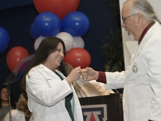 Erika Yee receives a fist bump from Carlos Gonzales, MD, FAAFP, assistant dean of curricular affairs at the UArizona College of Medicine – Tucson.