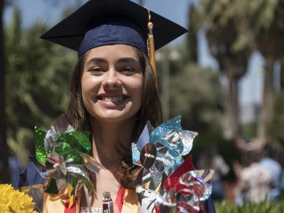 Joanna Schneider poses for a graduation photo with her flowers and pinwheels after receiving her Bachelor of Science in Nursing during the College of Nursing 2022 spring convocation at Centennial Hall.