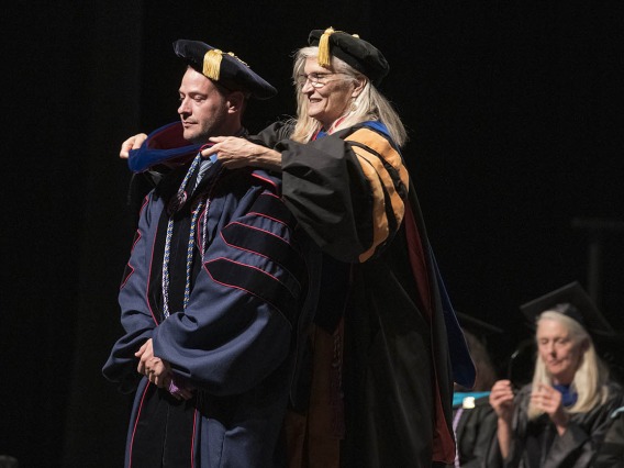 Monte Roberts, PhD, is hooded by Kimberly Shea, PhD, RN, CHPN, for earning his Doctor of Philosophy in Nursing during the UArizona College of Nursing 2022 spring convocation at Centennial Hall.