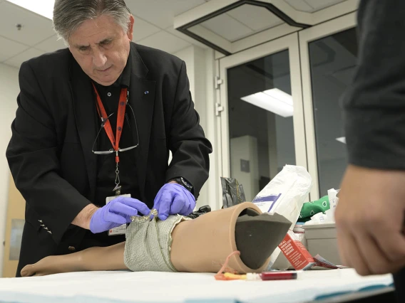 The director of the Arizona Simulation Technology and Education Center, demonstrates a field dressing for Doctor of Nursing Practice students.