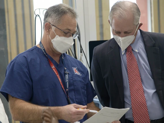 Jim Reed, DNP, CRNA, associate clinical professor, reviews the grading sheet he used while observing the CRNA students during a simulation with University of Arizona President Robert C. Robbins, MD. 