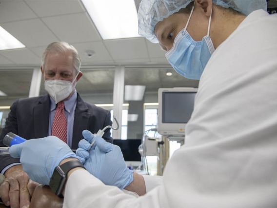 CRNA student Phillip Bullington, RN, (right) intubates a manikin as University of Arizona President Robert C. Robbins, MD, holds his hand on the “patient’s” throat to ensure that the procedure is successful. 