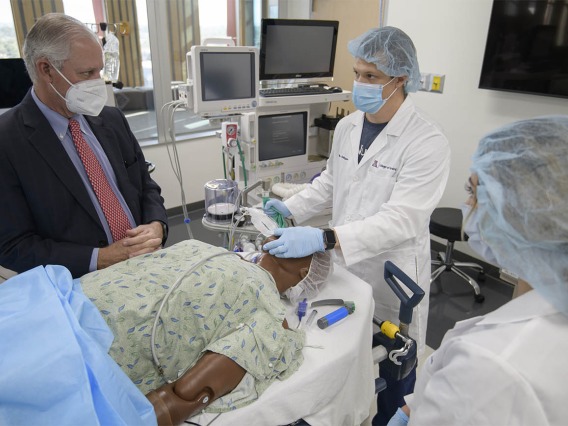 CRNA student Phillip Bullington, RN, (center), seeks input from University of Arizona President Robert C. Robbins, MD, during the simulation where the “patient’s” breathing was becoming very weak.  
