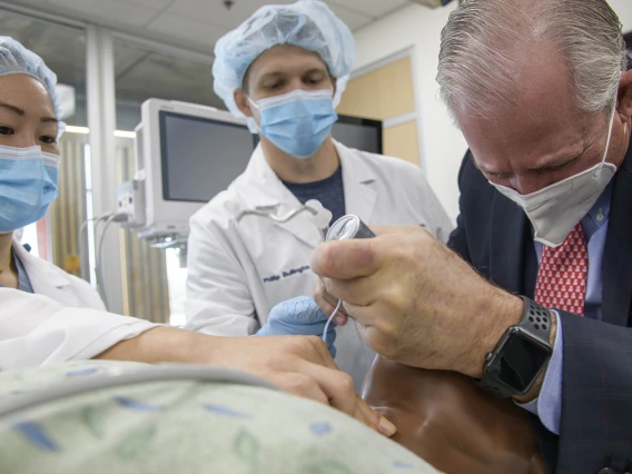 University of Arizona President Robert C. Robbins, MD, (right) recently visited the Arizona Simulation Technology and Education Center to observe second year Certified Registered Nurse Anesthetist (CRNA) students during their simulation. Instead of just observing, he was pressed into service as the surgeon during one simulation. CRNA students Alexa Deng, RN, (left) and Phillip Bullington, RN, assisted Dr. Robbins as he intubated a manikin. 