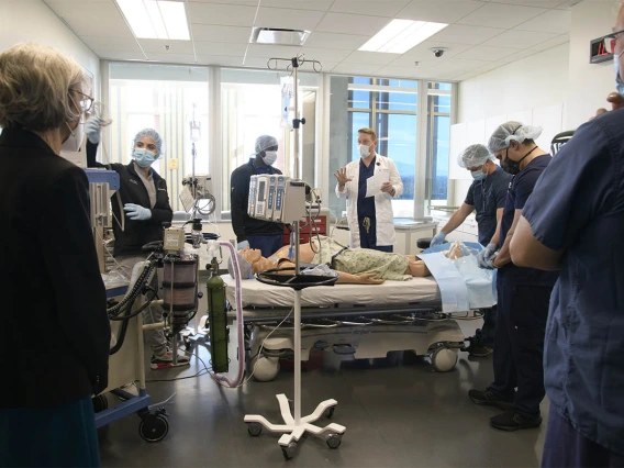 College of Nursing Dean Ki Moore, PhD, (left) listens as C. “Reggie” Elam, PhD, DNAP, CRNA, clinical assistant professor (white coat center), reviews how the CRNA students did in their first simulation of the day. 