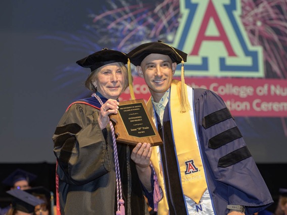 Jesus “JP” Prado, a Doctor of Nursing Practice graduate, is presented with the Outstanding DNP Project Award by Interim Dean Kathleen Insel, PhD, RN, during the UArizona College of Nursing fall convocation at Centennial Hall on Dec. 15. 