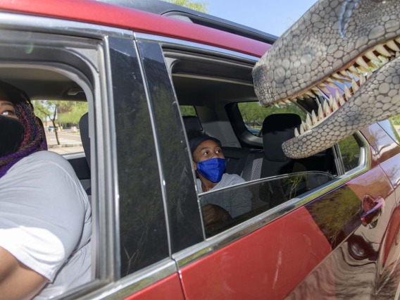 Doshia Davis, left, and Cy’Myah Murphy, keep a close eye on a nosey T-Rex as they begin the Connect2STEM drive-through event. 