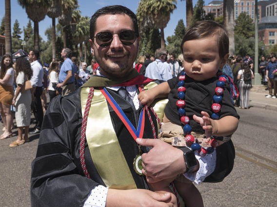 David Alvarado, PharmD, holds his son after the R. Ken Coit College of Pharmacy 2022 spring convocation at Centennial Hall.