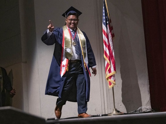 Bachelor of Science in Pharmaceutical Sciences graduate Kurt Carlos points to the audience as his name is called during the R. Ken Coit College of Pharmacy 2022 spring convocation at Centennial Hall. 