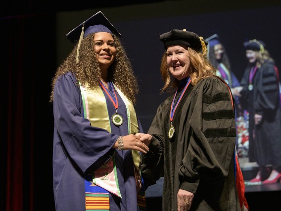 Jalynne Decker shakes hands with associate professor Jennifer Schnellmann, PhD, after receiving her Bachelor of Science in Pharmacological Sciences during the R. Ken Coit College of Pharmacy 2022 spring convocation at Centennial Hall.