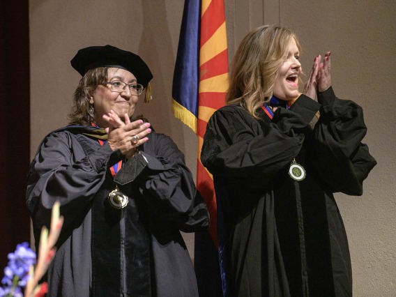 (From left) Nancy Alvarez, PharmD, BCPS, and Terri Warholak, PhD, RPh, applaud students as they walk across the stage during the R. Ken Coit College of Pharmacy 2022 spring convocation at Centennial Hall.