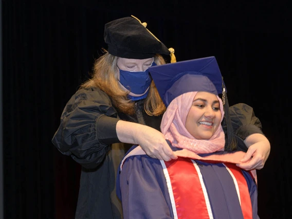 Master of Public Health graduate Javeria Ahmad is hooded by assistant professor of practice Christina Cutshaw, PhD, during the Mel and Enid Zuckerman College of Public Health fall convocation.