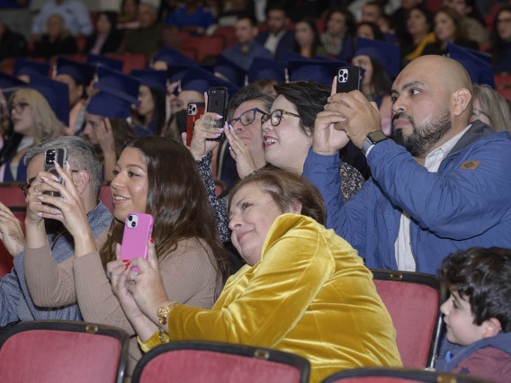 Italia Trejo’s family members wait to capture the moment she is hooded as a Master of Public Health graduate at the Mel and Enid Zuckerman College of Public Health fall convocation.