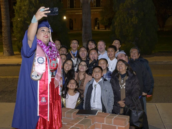 Bahozhoi Kinsel-Gishie takes a selfie with her family outside of Centennial Hall after receiving a Bachelor of Science in Public Health degree at the Mel and Enid Zuckerman College of Public Health fall convocation.